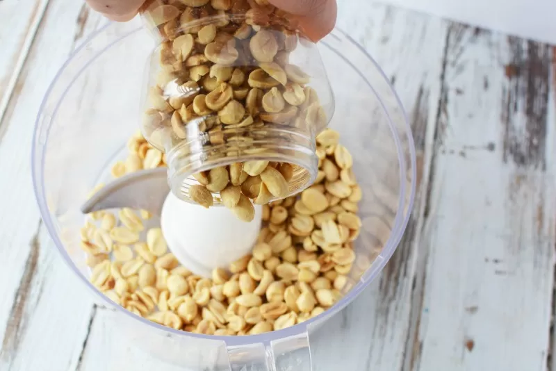 Adding nuts to a food processor to make homemade peanut butter