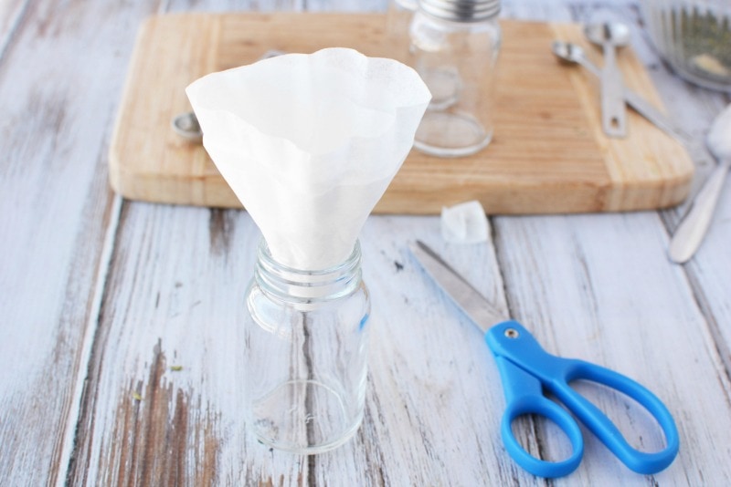 Using a DIY Coffee Filter Funnel to add DIY spices to jars.