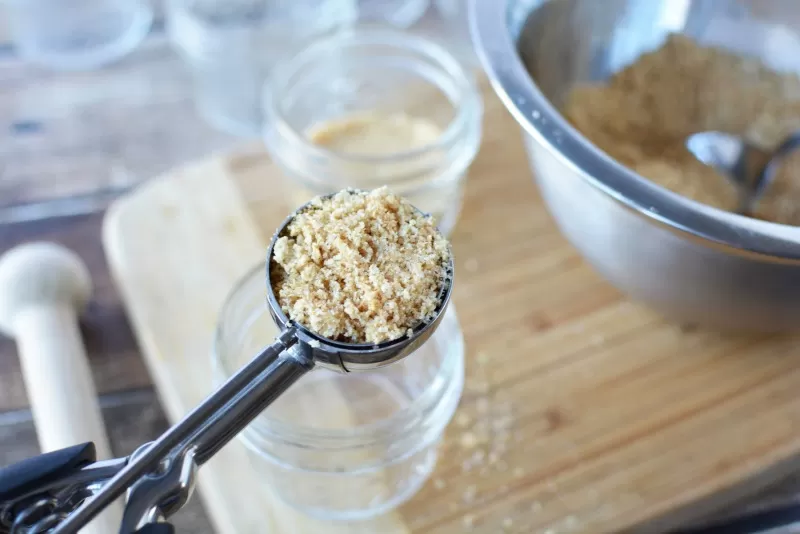 Spooning graham crackers into jar for Cheesecake in a Jar recipe