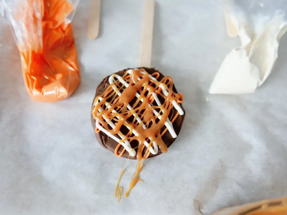 Adding caramel on top of caramel apple pops