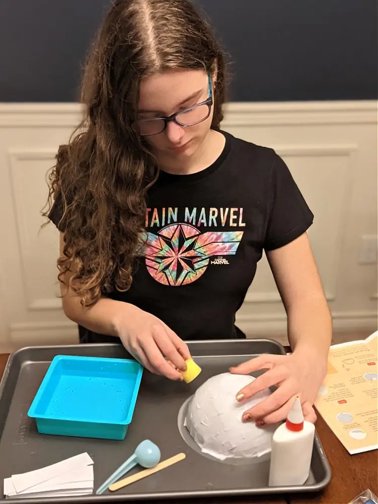 Gluing on the paper strips for handcrafted bowl from KiwiCo