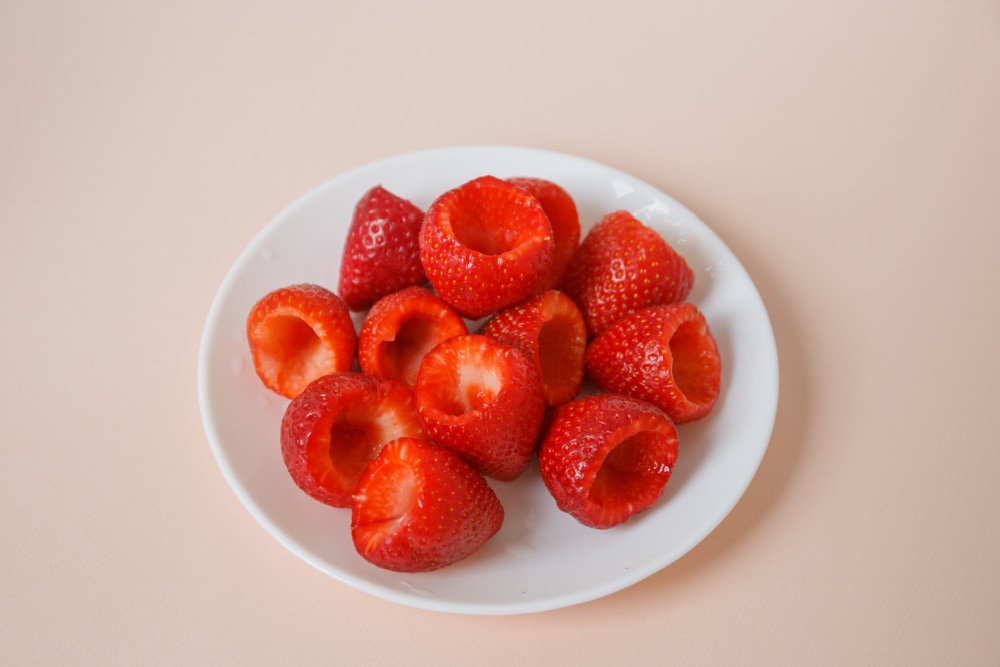 Cutting tops off of strawberries for cheesecake bites
