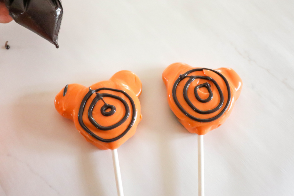 Making circles on Halloween Oreo Pops for spider webs